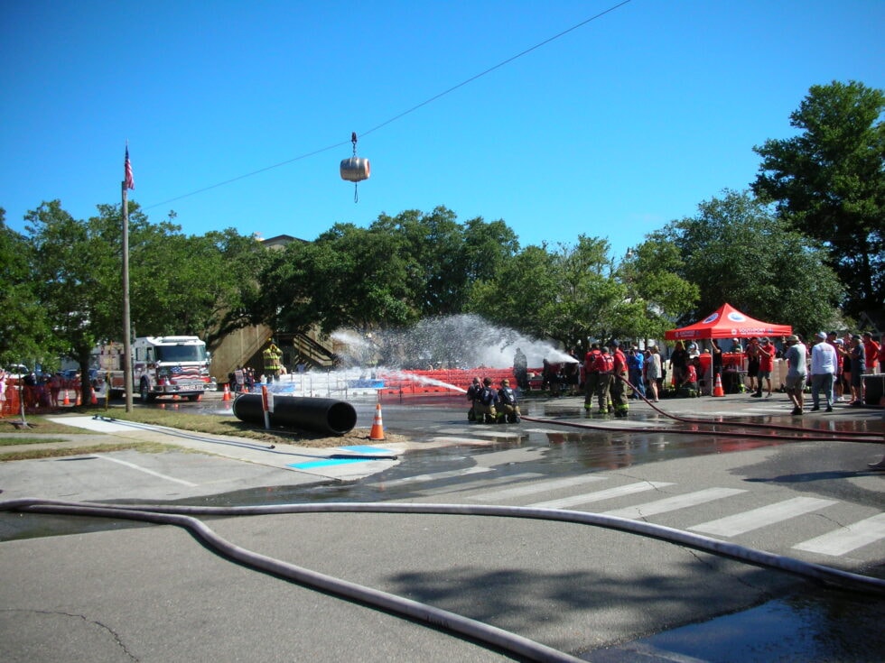 Wide shot of the water target challenge with hoses arcing across the Southport competition course and a barrel suspended overhead