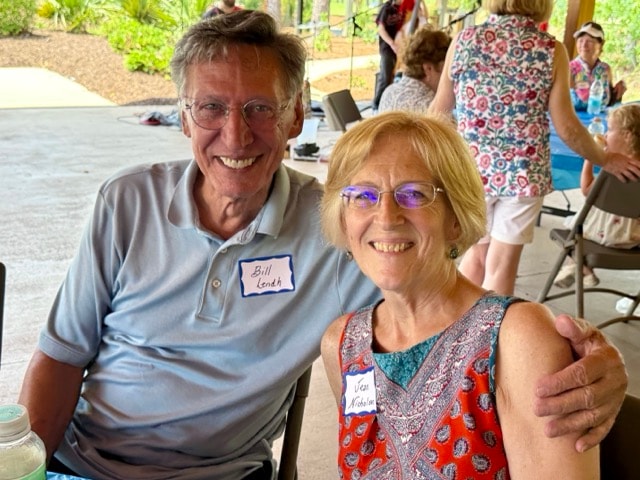 Bill Lendh and Jean Nicholas smile together at a picnic table under the pavilion