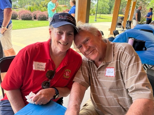 Helen Keohane in her SJFD Fire Police red shirt and SJFD cap leans in with Patrick at the picnic pavilion