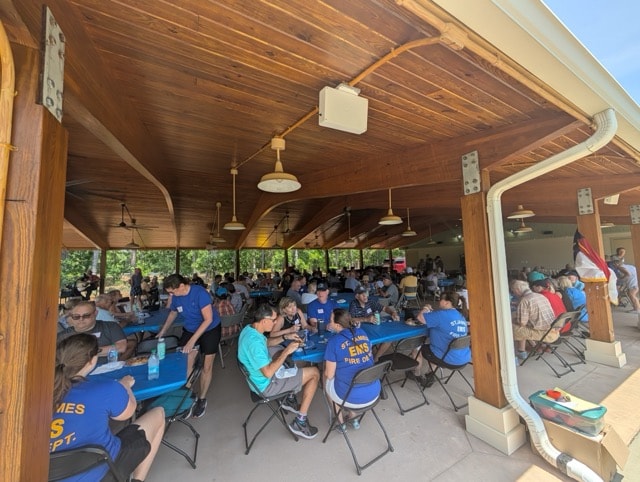Wide interior shot of the Woodlands Park Pavilion packed with SJFD volunteers and families in blue and red department shirts
