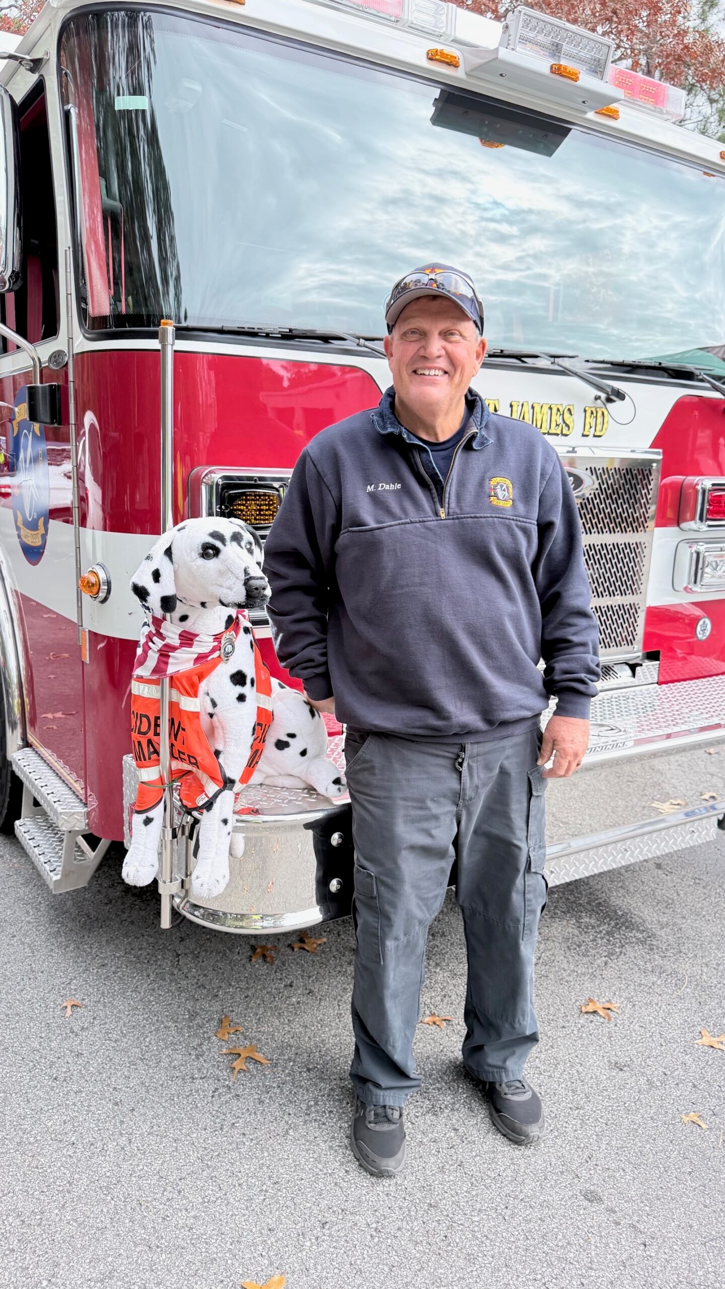 SJFD volunteer Mike Dahle standing with the Sparky dalmatian mascot in front of the St. James FD fire engine